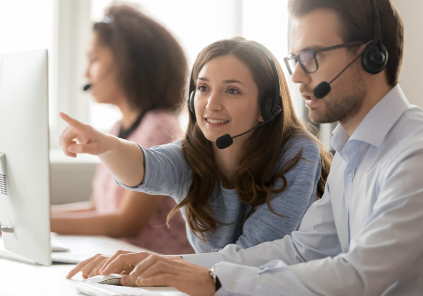 Female call center agent operator telemarketer helping male colleague