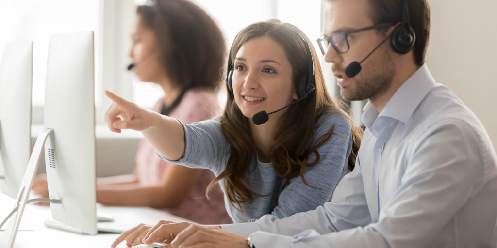 Female call center agent operator telemarketer helping male colleague